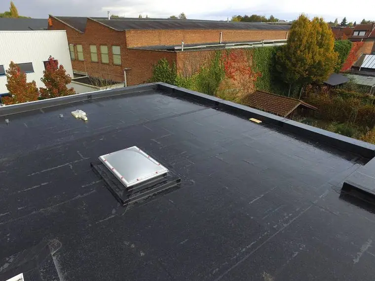A dark flat roof membrane with a new rooflight